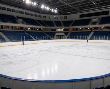 Photography of a modern collegiate ice rink in a North American / US Southern university city, wide angle showing clean white ice and blue stadium seating, professional lighting.