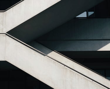 An abstract architectural photograph of a staircase in a modern corporate building, using a palette of dark navy and off-white, with clean lines and sharp shadows, global business style.