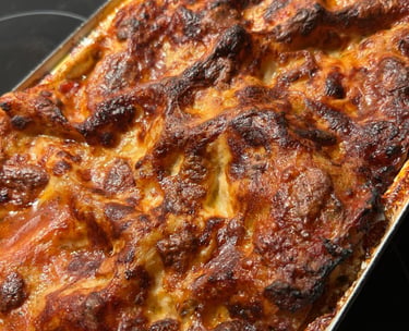 A close-up, top-down view of a freshly baked, bubbling, golden-brown lasagna with crispy cheese and rich tomato sauce