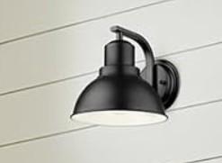 Matte black gooseneck barn light wall sconce mounted against white shiplap.