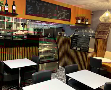 a restaurant with tables and chairs and a counter displaying cakes and pastries