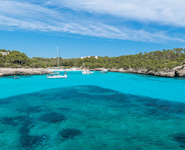 Una cala del sur de Mallorca, con aguas turquesas cristalinas, con veleros fondeando