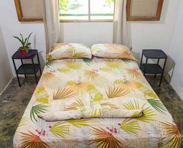 a bed with a bed and a table with a plant in it. Hostal Palomino EcoHouse