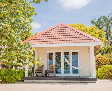 a small white house on the beach in Belize with a hammock
