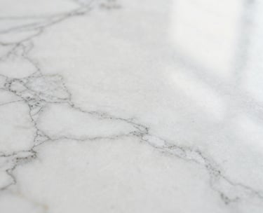 Detail of a white marble surface with light reflecting, soft and airy aesthetic, high-end branding mood.