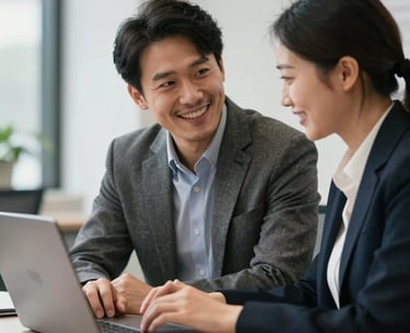 A professional mentor and a client in a North American office setting looking at a laptop screen together, smiling and engaged in positive conversation.