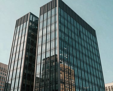 A modern glass-and-steel professional building in a North American business district, captured in clean, bright daylight with teal and charcoal tones.
