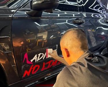 Technician applying custom pink lettering decal on car door panel