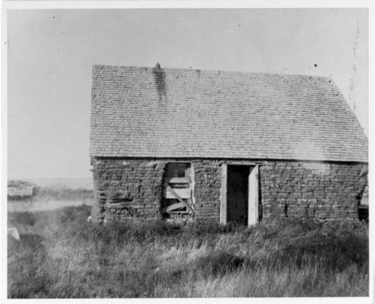 a black and white image of a sod house on the prairie