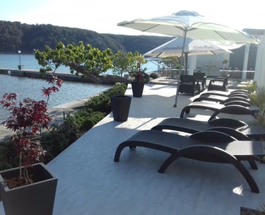 Sonnenliegen mit Sonnenschirmen auf einer Terrasse bei einem Luxusapartment in Kampor auf Rab