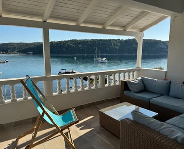a couch and chair on a porch with a view of the water