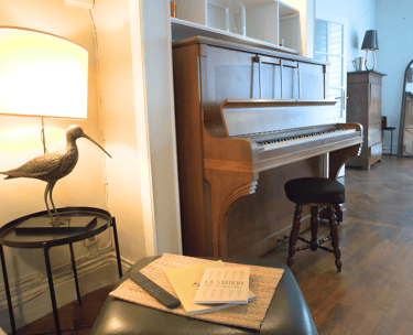 Espace de vie chaleureux avec piano en bois dans maison meublée pour groupes.