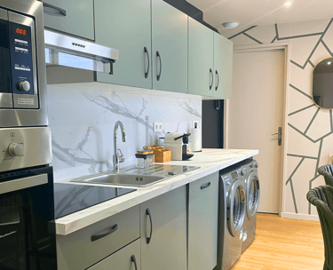 Cuisine équipée moderne avec électroménagers et plan de travail marbré dans maison meublée.