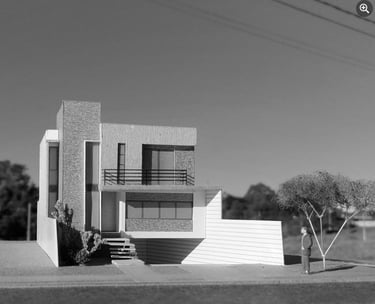 Maquete de casa moderna com fachada volumétrica e elementos verticais em destaque