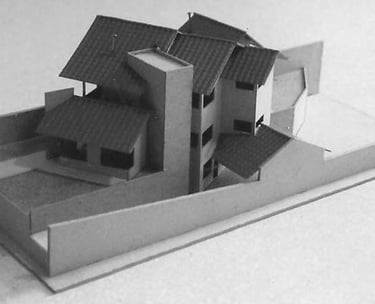 Maquete física de residência com telhado inclinado e volumetria em múltiplos níveis