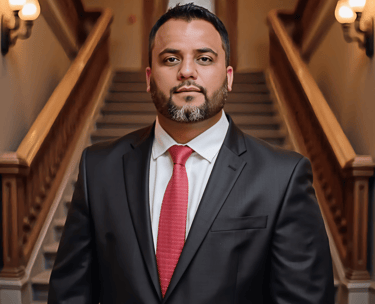 a man in a suit and tie standing in front of a staircase