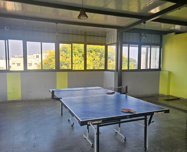 Table tennis area with a table, net, and surrounding floor space.