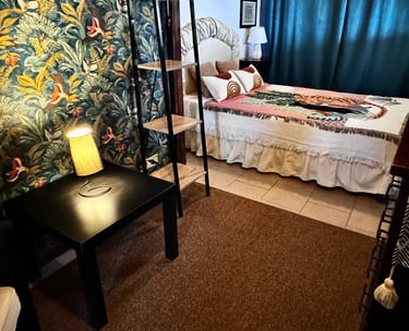 Cozy guest bedroom with tropical wallpaper and reading lamp in beachfront villa Siracusa, Sicily