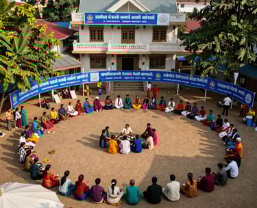 A high-angle photo of a vibrant community gathering in a South Asian rural town square, featuring clean surroundings and blue banners representing public service.