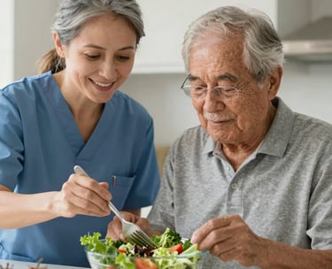 A close-up of a senior resident and a caregiver in a bright North American kitchen preparing a fresh salad together, symbolizing relationship-centered care and dignity.