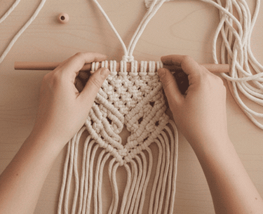 manos tejiendo con la ´tectica macramé, los hilos son de color crudo