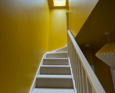 colour drenched stairwell to loft, bright yellow gloss paint and skylight creates very bright area