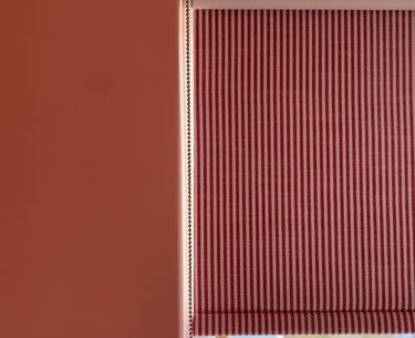 coral pink walls and striped red roller blinds creating a fun yet mature bedroom