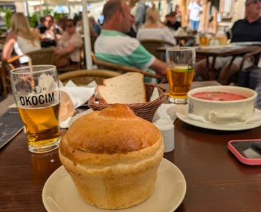 a table with a Żurek w chlebie and beer in a restaurant