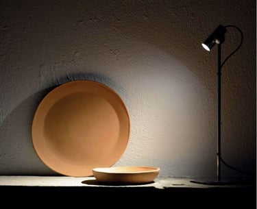 Foco de iluminación puntual destacando elementos decorativos sobre pared de textura natural