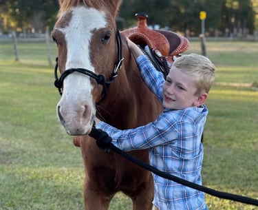 Smiling first grade cowboy hugging Snickers at a pony ride birthday party