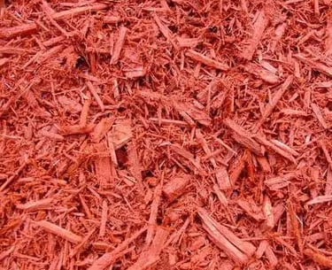 Close-up of vibrant red dyed wood mulch chips for professional landscaping and garden ground cover.