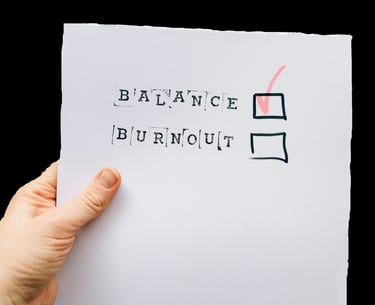 📝 Checkbox list with the words "Balance" and "Burnout" — hand ticking "Balance"