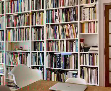 a laptop computer sitting on a table in front of a bookshelf