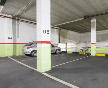 Imagen de un garaje con un  vehículo y bicicleta, con las paredes con franjas verde, rojo y blanco.