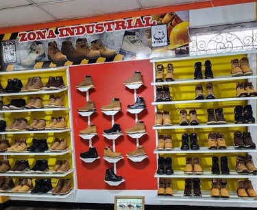 Botas de seguridad y calzado industrial de alta resistencia exhibidos en estantes blancos.