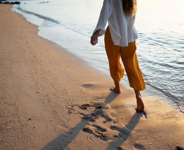 a sugar mommy walking on the beach with her feet in the sand