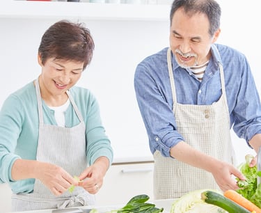 une femme et un homme souriant occupés a préparer un repas.