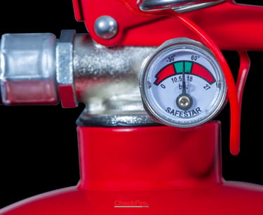 Close-up of a red fire extinguisher pressure gauge showing needle in the green zone for safety.