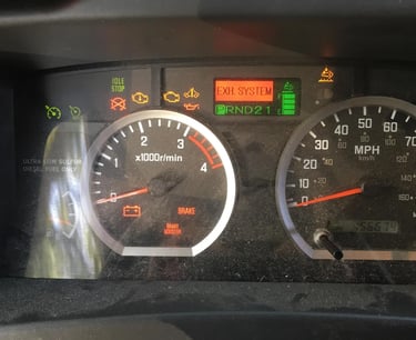 Truck dashboard displaying active warning lights including exhaust system, battery, and brake alerts.