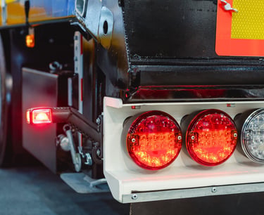 Close-up of red and white LED tail lights on a heavy-duty semi-truck trailer.