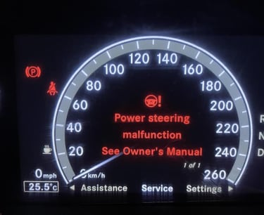 Digital car dashboard displaying a red power steering malfunction warning message and service alert.