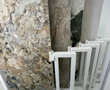 Showroom display featuring large-format marble and porcelain tiles on white metal sliding racks.