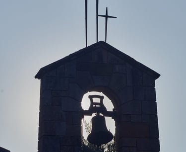 Campanario de piedra con tres cruces al amanecer.
