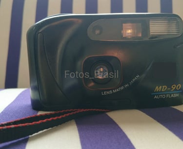 Sobre uma almofada está a majestosa, uma câmera fotográfica de filme do final dos anos 90