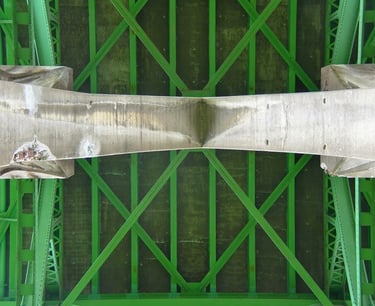 underside of a bridge with concrete supports and green rafters