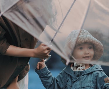 Uma mãe ajudando a filha a segurar um guarda-chuva para se proteger
