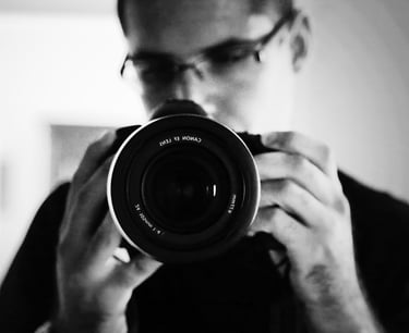 Autoportrait du photographe avec l'appareil photo au premier plan.