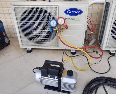 Vacuum pump and manifold gauges connected to a Carrier inverter AC unit for HVAC maintenance and repair.