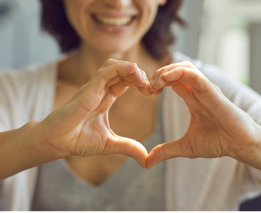 Mujer sonriendo haciendo con sus manos la forma de un corazón