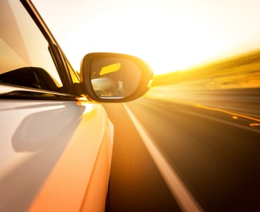 Auto siendo conducido en una amplia carretera en el atardecer